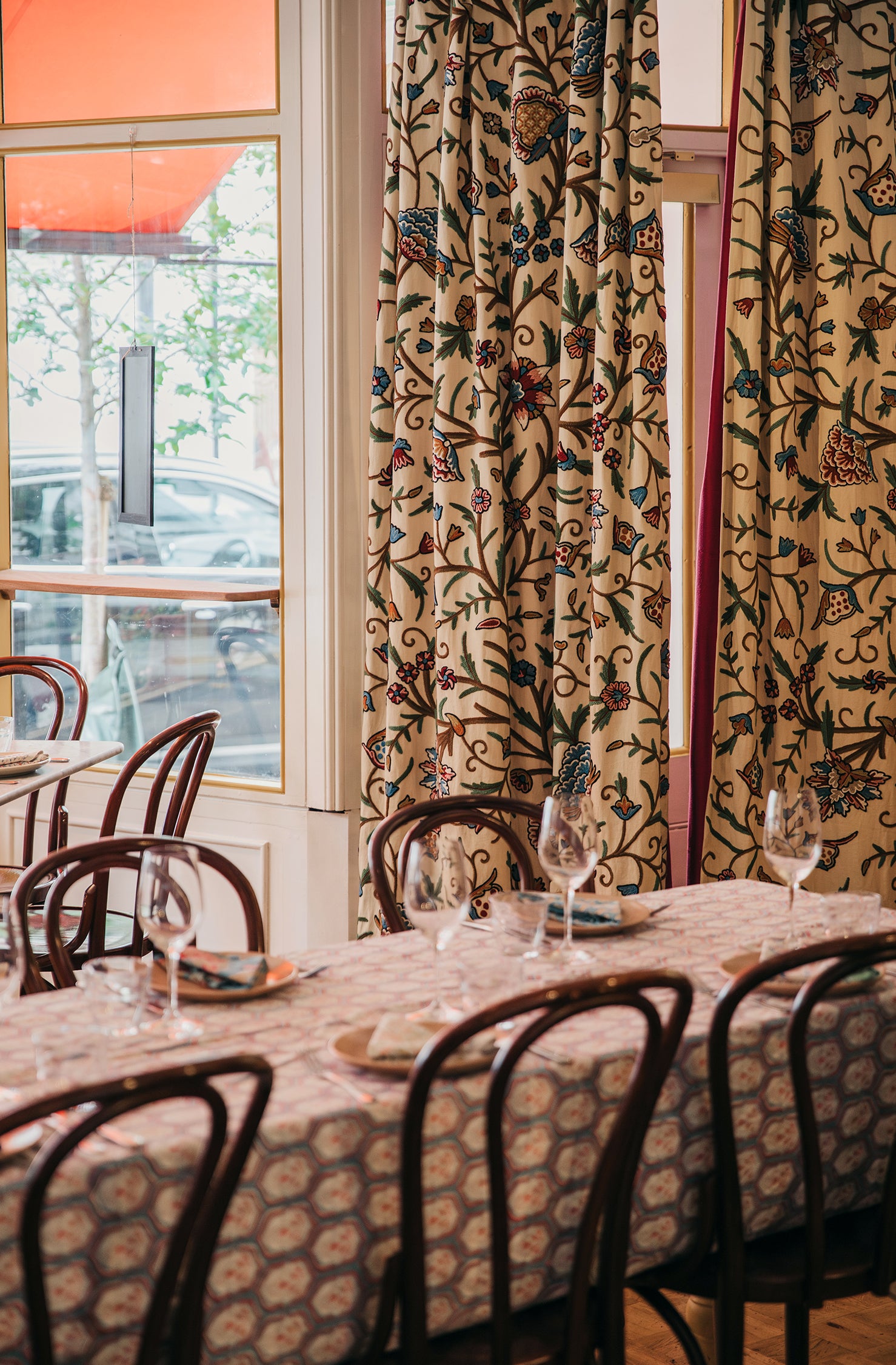 Dining area with patterned tablecloth, chairs, and curtains in a restaurant setting.