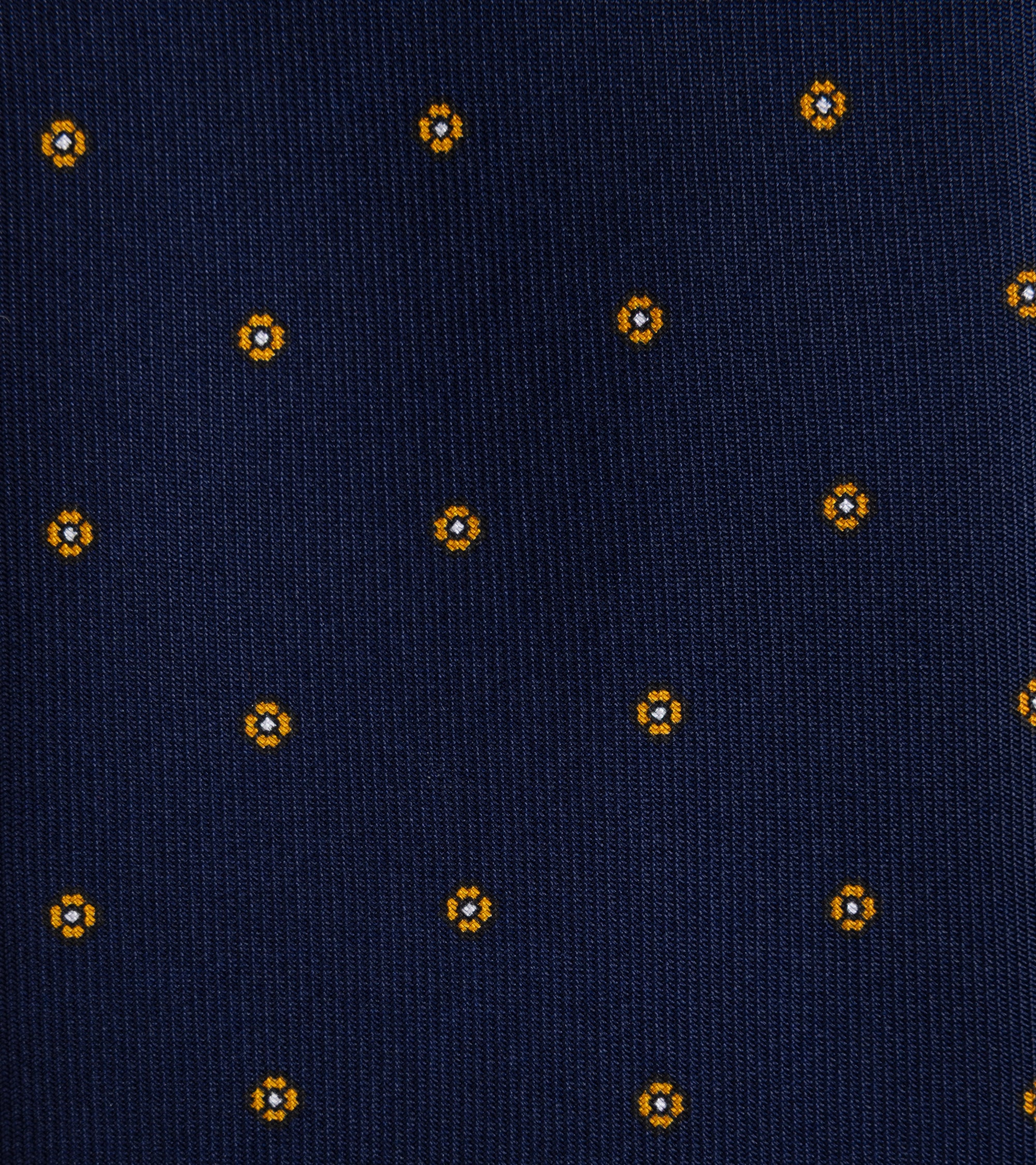 A close-up of a dark green woven fabric with a repeating small geometric floral pattern in yellow.