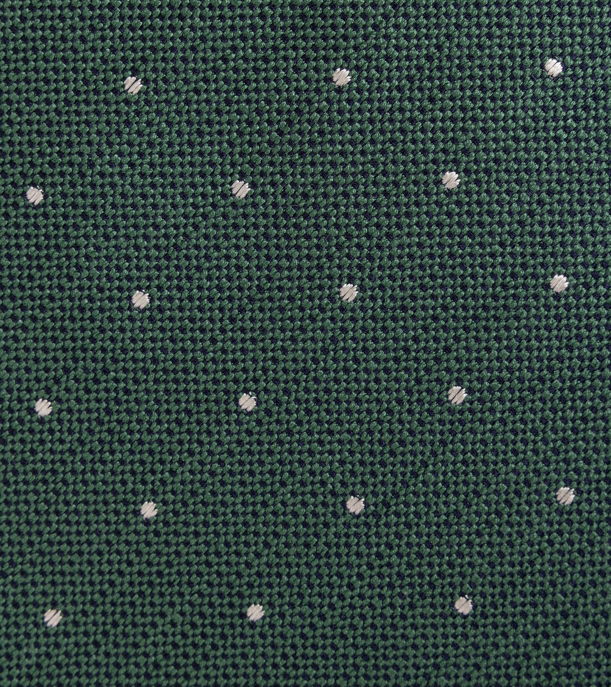 A close-up of a sage green woven fabric with a repeating pattern of small white embroidered dots.