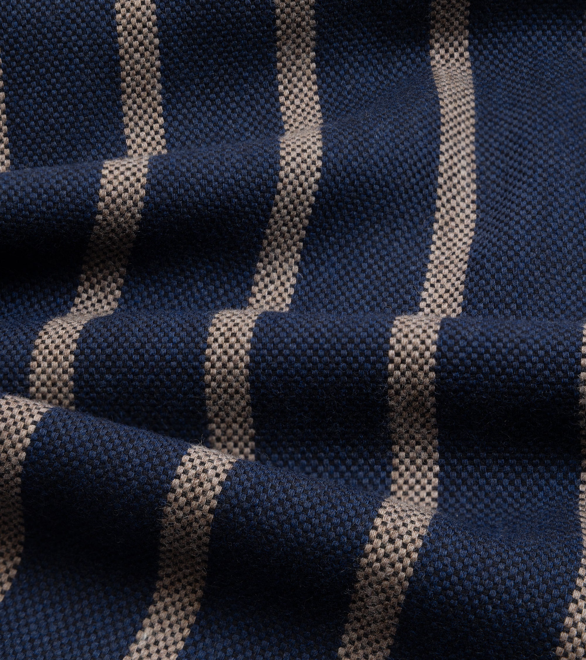 A close-up of woven fabric with dark blue and beige vertical stripes, showing the texture and pattern details.